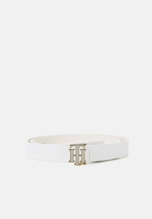 Ceinture en cuir blanc avec boucle métallique dorée à double T entrelacée, posée à plat sur un fond clair.
