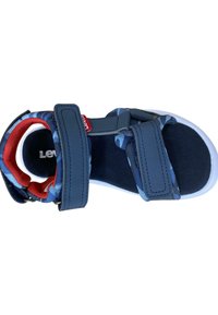 Sandalia azul y negra con correas de velcro, suela de goma, plantilla acolchada y acentos rojos en el forro interior. Diseño ligero y abierto.