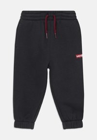 Pantalons de survêtement noirs en tissu doux, avec une taille élastique dotée d'un cordon de serrage bordeaux, des jambes fuselées et un petit patch avec le logo rouge de Levi's.
