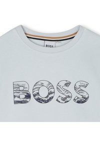 Light blue cotton crew neck t-shirt featuring a bold, textured "BOSS" logo in dark blue with a marbled design. Short sleeves and tag visible.