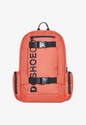 Orange stof rygsæk med sorte spænder og logo, polstrede stropper, sidelommer og et bærehåndtag for nem transport.