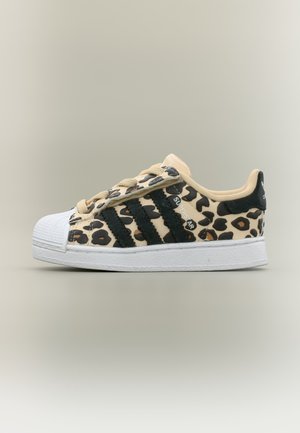 Niske Adidas Superstar tenisice s bež i crnim leopard uzorkom, crnim prugama, bež vezicama i bijelim gumenim vrhom i potplatom.