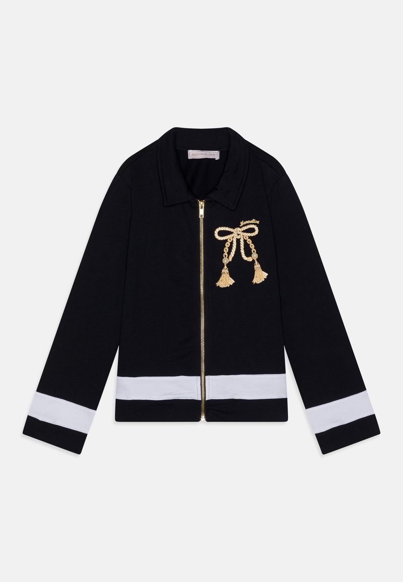 Veste noire zippée avec col, rayures blanches sur les poignets et l'ourlet, et un détail de nœud à pampille dorée sur le côté gauche de la poitrine. Tissu doux.