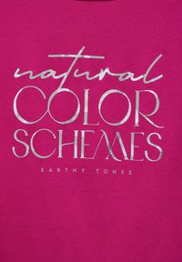 Fuchsiové tričko s metalickým stříbrným nápisem: "přirozené FARBENÉ SCHÉMY" a "ZEMSKÉ ODTÍNY" v různých písmenech a velikostech. Měkká textilie.