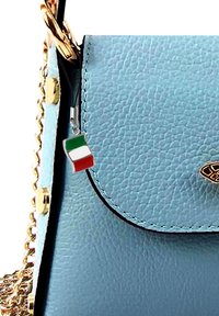 Lichtblauwe leren handtas met gouden hardware, voorzien van een kleine Italiaanse vlag charm aan de rits. Geweven oppervlak, klepdesign.