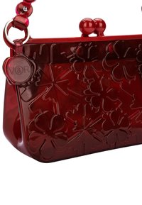 Rote transparente Handtasche mit floralem Prägedesign, runden Griffen und einem runden Logo-Akzent. Verfügt über eine glatte, glänzende Textur und eine strukturierte Form.