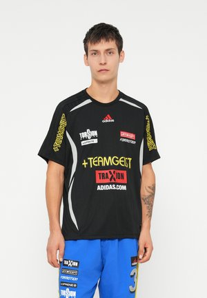 Sort sportsjersey med korte ærmer, prydet med sølvdetaljer og flerfarvede logoer, herunder "TEAMGEIST" og "ADIDAS."