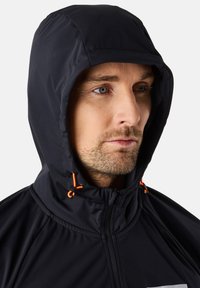 Schwarze Kapuzenjacke mit verstellbaren orangen Zugbändern, Reißverschluss und strukturiertem Finish, mit geometrischem Design auf der Vorderseite.