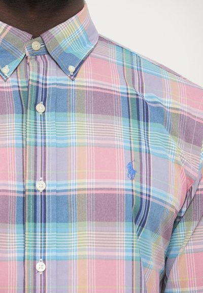 Srajca s karirastim vzorcem v več pastelnih tonih, z belimi gumbi, modro vezenim logotipom ter standardnim ovratnikom. Tkanina z teksturirano obdelavo.