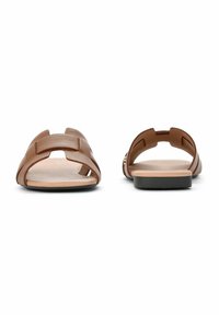 Brązowe skórzane sandały z otwartym noskiem, z wycięciami i płaską podeszwą. Posiadają lekką, teksturowaną wkładkę oraz minimalistyczny styl.