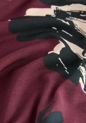 Mørkerød stof med en glat tekstur, der har abstrakte sorte og cremefarvede blomster mønstre. Designet viser bløde folder og draperinger.