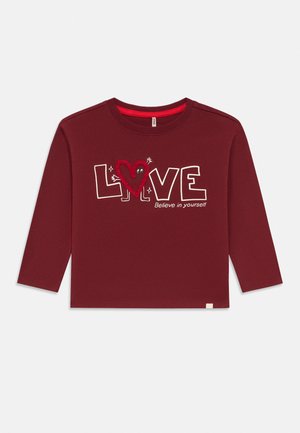 Burgunderfarget langermet skjorte med teksten "LOVE", hjerteformet tegn som erstatter "O," og slagordet "Tro på deg selv" foran.