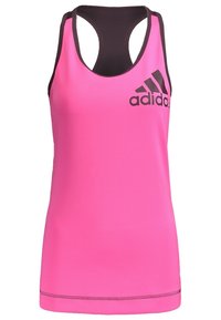 Różowy sportowy top na ramiączkach z tyłem typu racerback. Na piersi znajduje się czarne logo Adidas. Wykonany z gładkiego materiału o dopasowanym kroju.