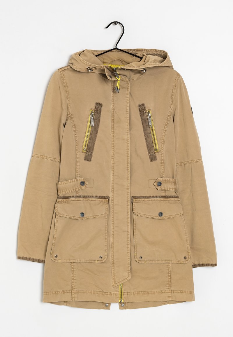 Veste à capuche marron clair avec fermeture éclair à l'avant, deux poches supérieures zippées et deux poches inférieures à rabat, suspendue à un cintre noir sur un fond blanc.