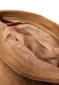 Zachte bruine suède hoed met een gladde, lichtbruine voering aan de binnenkant en zichtbare stiksels langs de rand van de klep.