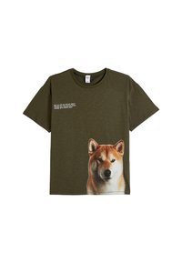 Oliwkowa bawełniana koszulka z dużym graficznym wizerunkiem psa Shiba Inu z przodu i białym napisem powyżej. Okrągły dekolt, krótki rękaw.