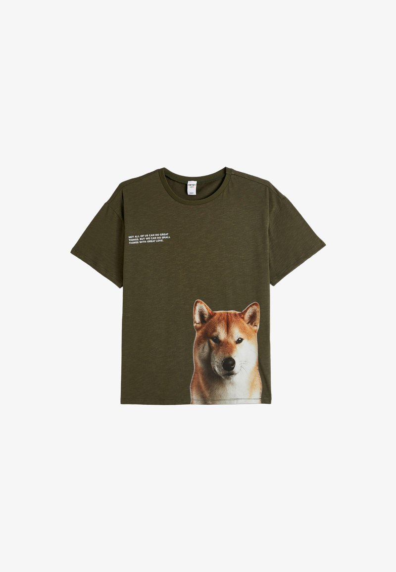 Camiseta de algodón verde oliva con un gran gráfico de un perro Shiba Inu en la parte frontal y texto blanco arriba. Cuello redondo y mangas cortas.