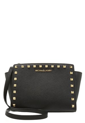 Schwarze Michael Kors Umhängetasche mit goldenen quadratischen Nieten, die die Vorderseite umranden, und einem schlanken Schulterriemen.