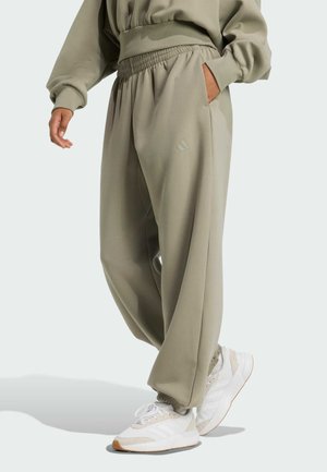 Gröna sweatpants med elastisk midja och sidofickor, med en subtil logodetalj. Kombineras med grå och vita sneakers.
