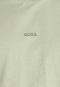 Világoszöld pamut póló, kerek nyakkivágással és diszkrét, sötétzöld "BOSS" logóval, a mellkason középre elhelyezve.