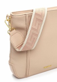 Różowa torebka ze skóry z teksturowanym wykończeniem, złotymi okuciami i wzorzystym paskiem z tkaniny z jasnoróżowymi i białymi akcentami.