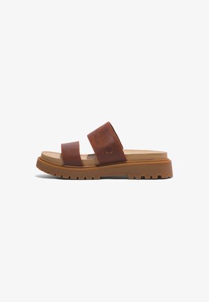 Sandalias de cuero marrón deslizantes con dos correas anchas, una suela acolchada y una suela de goma estriada para mayor tracción. Logo de Timberland grabado.