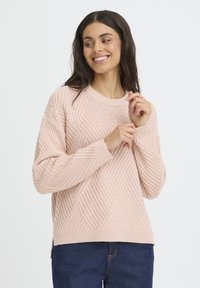 Ljusrosa stickad tröja med ett strukturerat diamantmönster, rund halsringning och ribbade ärmslut, med sidslitsar vid fållen.