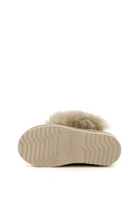 Vue unique d'une chaussure beige à enfiler avec un motif de semelle en zigzag et une tige en laine duveteuse portant l'étiquette "Warrnbal Australia".