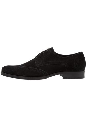 Schwarzer Wildleder-Oxford-Schuh mit schlanker Silhouette, Schnürdesign und dekorativen Broguing-Akzenten entlang der Seiten und der Zehenpartie.