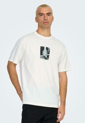 T-shirt bianco a maniche corte con una grafica quadrata in bianco e nero al centro che raffigura una mano e una palla. Materiale in cotone morbido.
