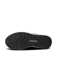 Black rubber shoe sole with a patterned tread providing traction; features speckles in the rubber and a green accent label.