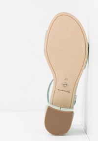 Semelle de sandale pour femmes vert clair avec bride de cheville, taille 37, semelle lisse couleur tan, et une petite patin texturé au talon.