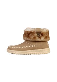 Botín beige con un puño de pelo sintético, detalles de costura y una suela de goma texturizada. Presenta una tira lateral con un botón metálico circular.