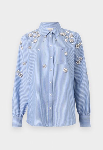 Blå og hvid stribet skjorte med knapper foran, lange ærmer og sølvfarvede blomstermotiver spredt over skuldre og ærmer.