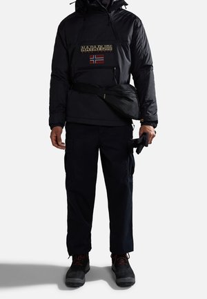 Black insulated pullover jacket with zippered pocket, featuring a logo and Norwegian flag. Paired with dark cargo pants and black boots.