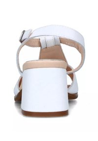 Sandali con tacco in pelle bianca, con cinturino alla caviglia e chiusura con fibbia. Tacco quadrato e spesso, superficie liscia e retro scoperto.