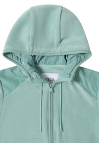 Veste en polaire bleu clair avec capuche, fermeture éclair à l'avant, cordons de serrage et panneaux renforcés aux épaules.