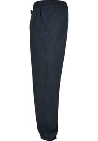 Pantalon décontracté bleu marine avec taille élastique et poignets aux chevilles, poches latérales, vu de profil sur fond blanc.