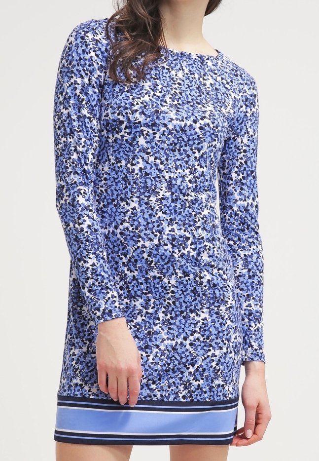 Långärmad klänning i blå blommönster med vita detaljer, med en enfärgad blå fåll och marinrandiga detaljer. Tyget verkar slätt och lätt.