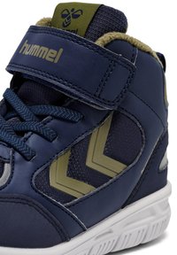 Marineblauwe hoge sneaker van synthetisch leer met gestructureerde accenten, voorzien van een groen logo, klittenbandsluiting en contrasterende witte zool.