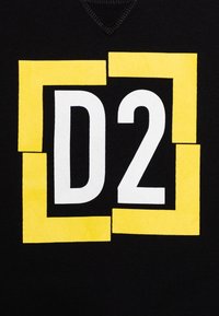 Tela negra con un gran diseño gráfico que presenta la letra "D" y el número "2" en blanco, enmarcados por rectángulos amarillos.