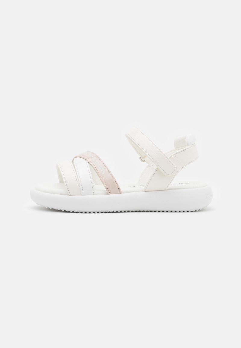 White sandal with three adjustable straps; one is light pink. Features a textured white sole and a soft inner lining, designed for comfort.