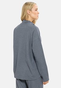 Harmaa, ribattu pitkähihaistoppi rentoa istuvuutta ja korkeaa kaula-aukkoa, jossa on roikkuvat olkapäät ja sivuhalkiot liikkuvuuden helpottamiseksi.