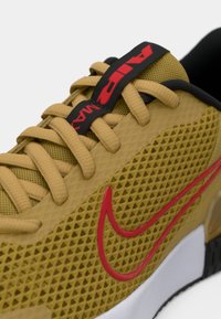 Nike Air Max sneakers i struktureret gul mesh, med røde Swoosh-logo, sorte detaljer og beige snørebånd på en hvid og sort sål.