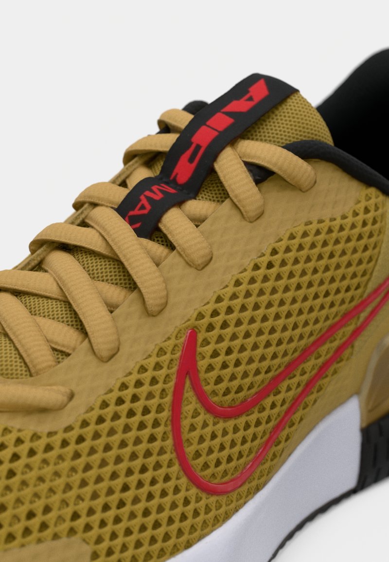 Zapatillas Nike Air Max en malla texturizada amarilla, con el logo Swoosh rojo, detalles negros y cordones beige sobre una suela blanca y negra.