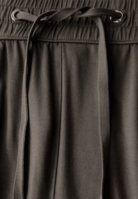 Pantaloni jogger di colore grigio scuro con una texture morbida, vita elastica e cordoncino con occhielli metallici per la regolazione.
