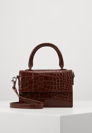 Mała prostokątna ciemnobrązowa torebka ze skóry wzór krokodyla, z górnym uchwytem i odpinanym paskiem na ramię, na białej powierzchni.