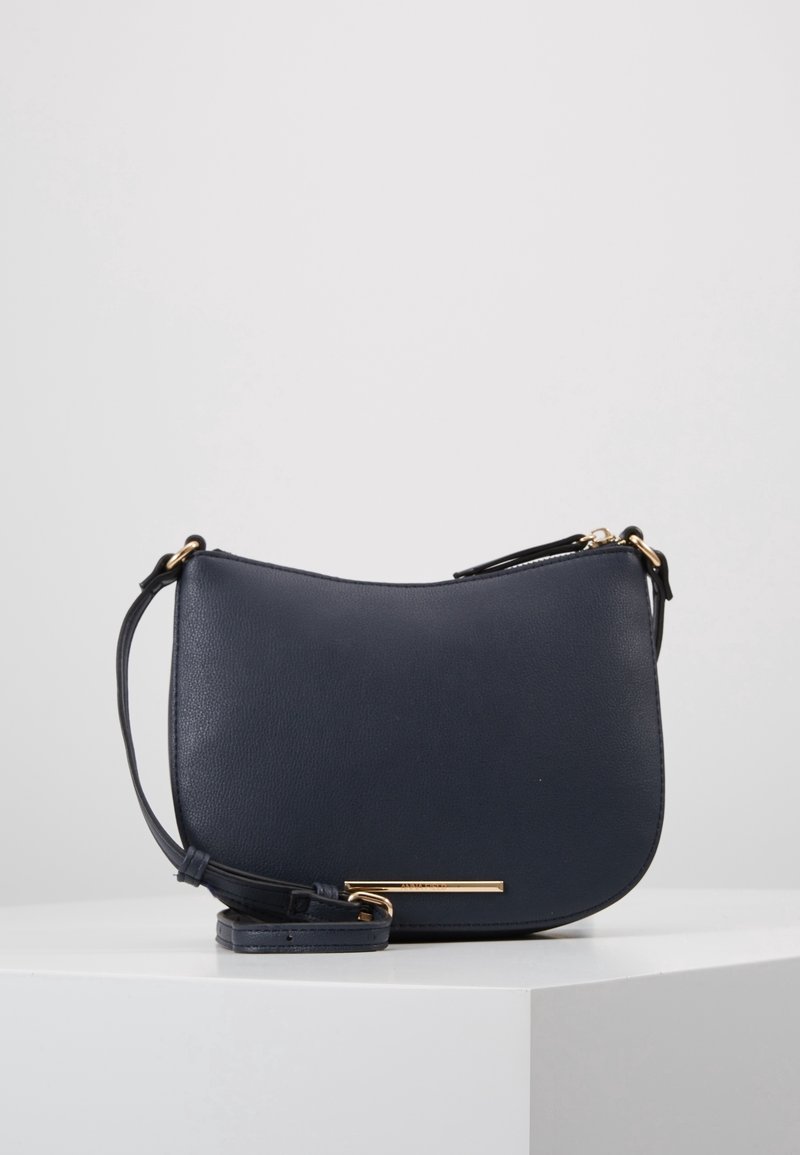 Námořnická kožená crossbody taška s hladkým povrchem, zakřiveným siluetem, nastavitelným popruhem a zlatavým kováním.