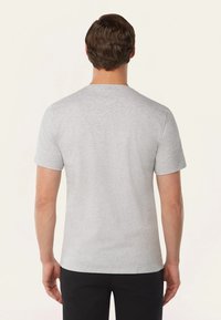 Grijs T-shirt met korte mouwen, gemaakt van zachte katoen. Het heeft een ronde hals en een schoon, eenvoudig ontwerp zonder patronen of versieringen.