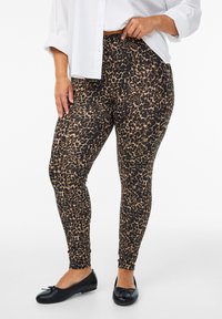 Leopardmønstrede leggings i blødt, strækbart stof med en høj talje design. Bæres med en løs hvid skjorte med knapper og sorte flade sko.
